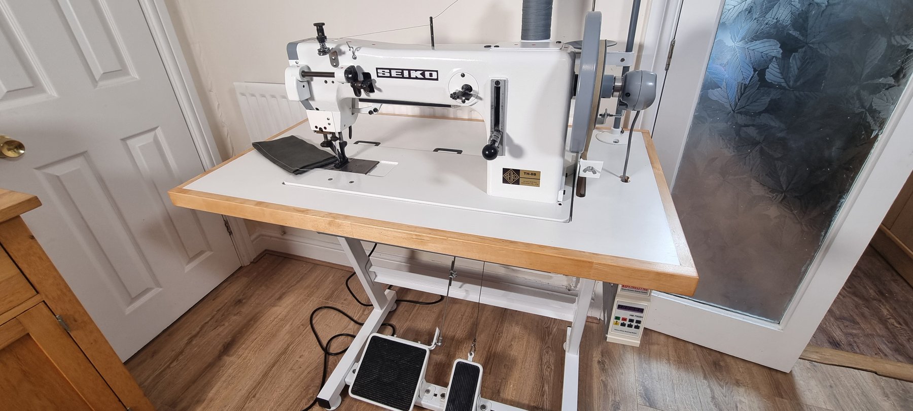 Restored Seiko TH-8B industrial sewing machine on white table with hardwood edge trim
