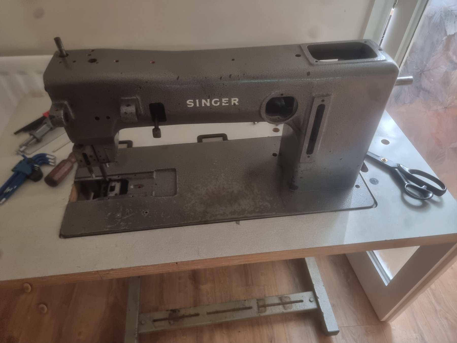 Stripped grey Singer 45B8BT cast-iron sewing head on the workshop table before respray