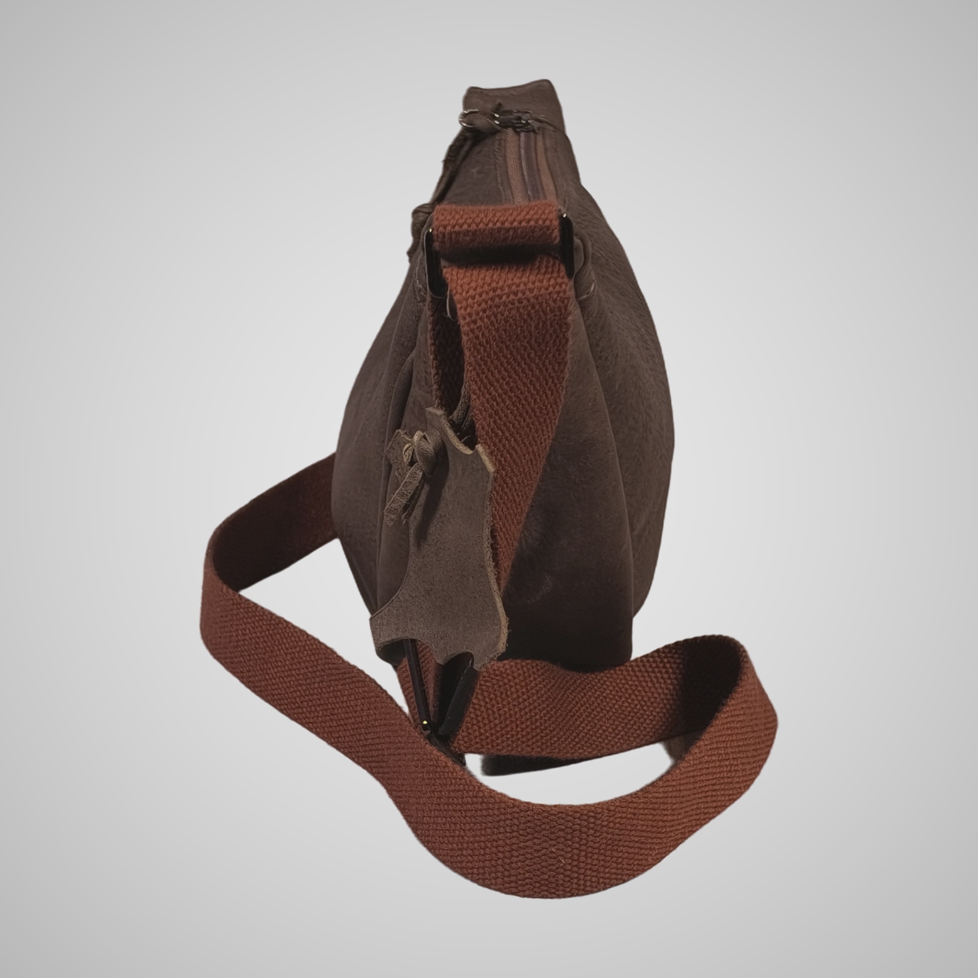Side view of Lumengin Half Moon cross-body bag in brown distressed leather with hide-shaped leather tag
