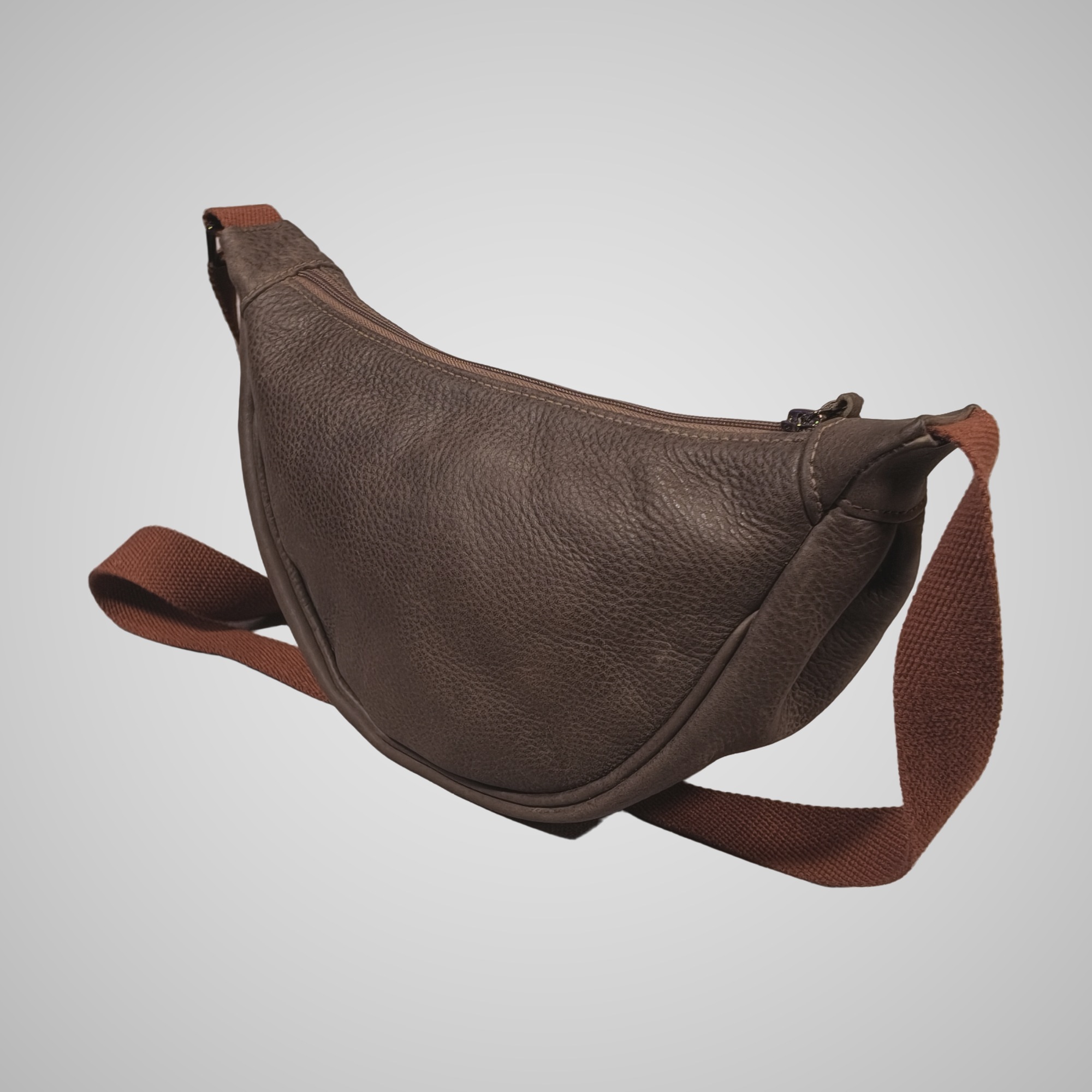 Three-quarter back view of Lumengin Half Moon cross-body bag in brown hand tipped distressed leather with adjustable strap