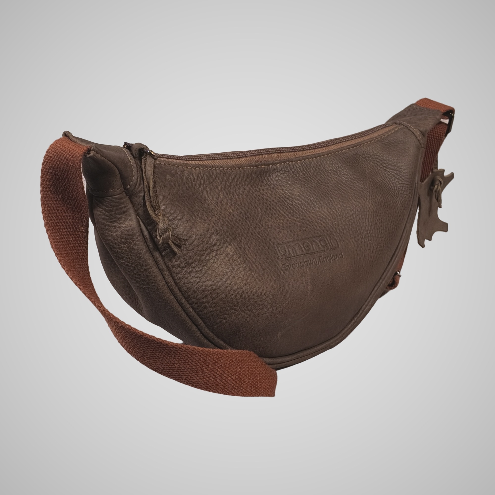 Angled view of Lumengin Half Moon brown distressed leather cross-body bag showing the hand tipped grain and zip