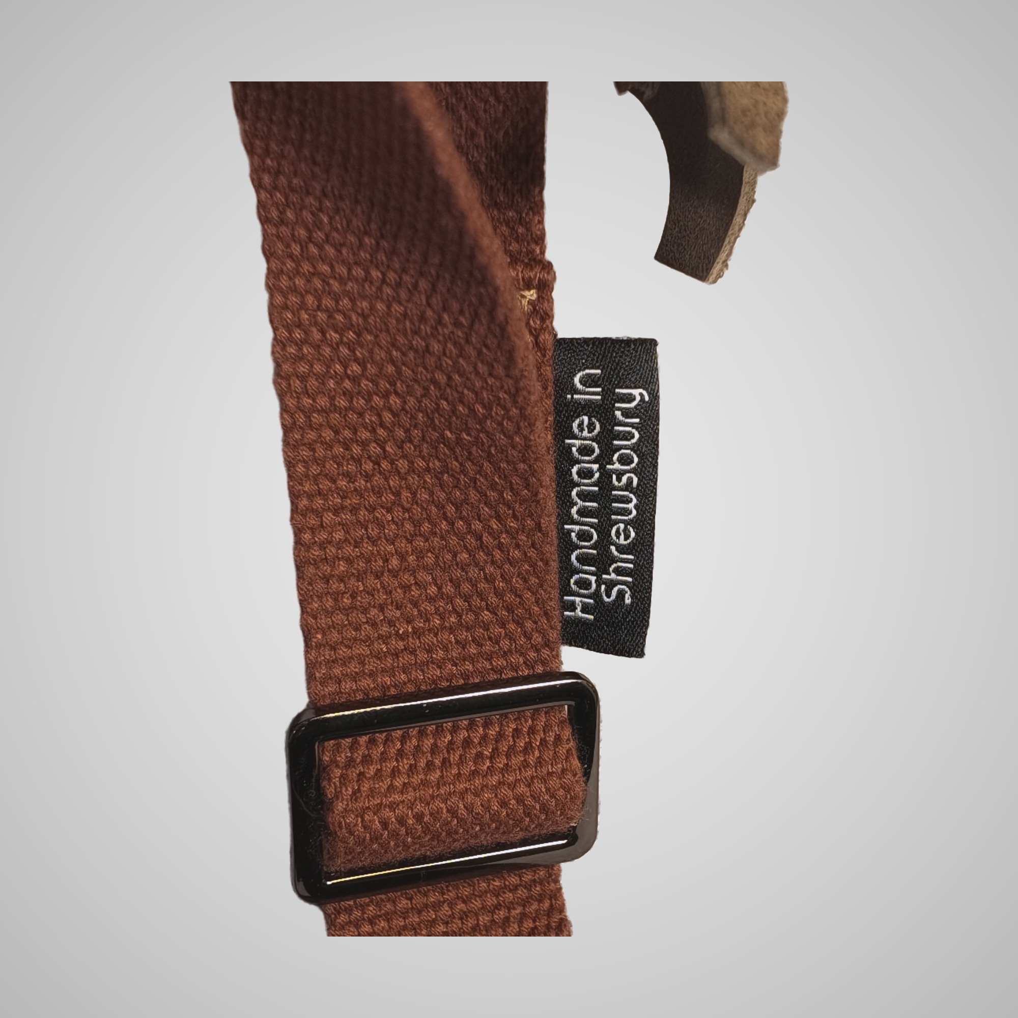 Close-up of rust webbing strap and buckle with Handmade in Shrewsbury label on Lumengin Half Moon cross-body bag