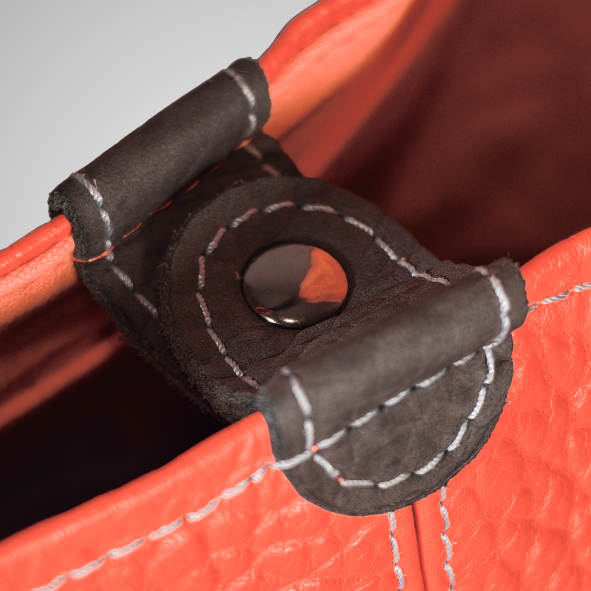Close-up of the dark grey leather tab with press stud on the Lumengin Bubble Orange medium hobo bag