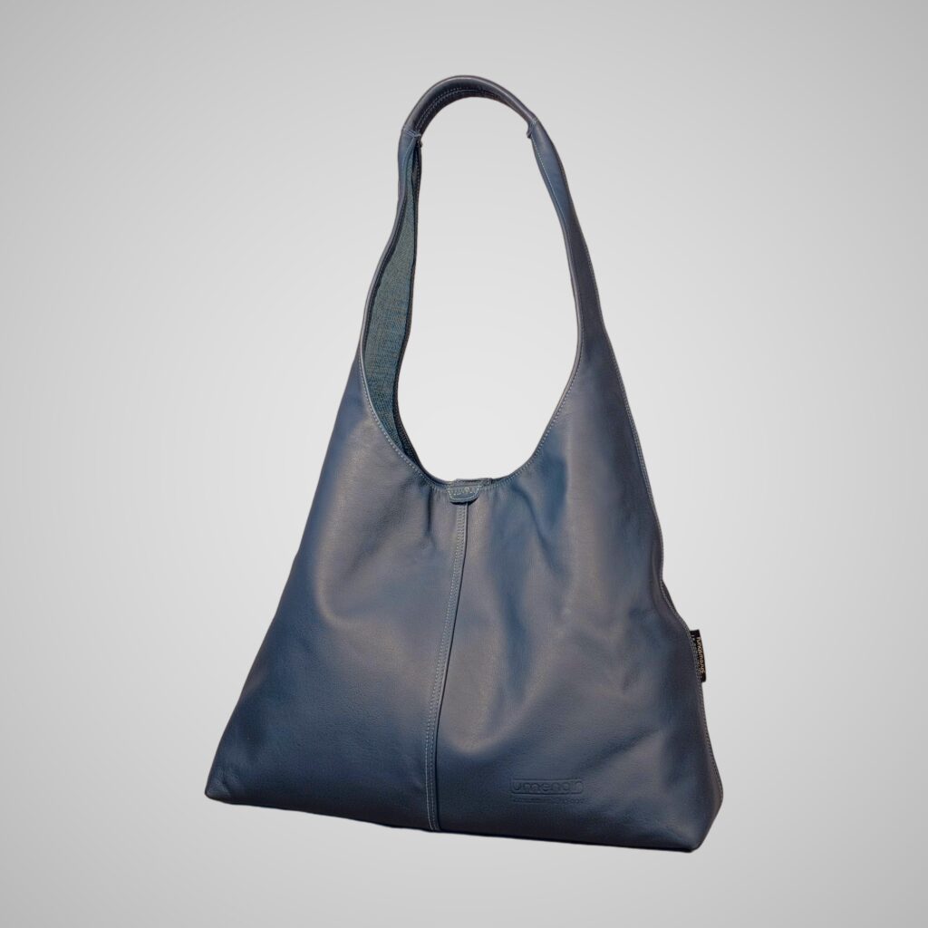 Front view of Lumengin XL hobo bag in marine blue-grey smooth Italian leather with stitched centre seam and embossed Lumengin mark, on soft grey