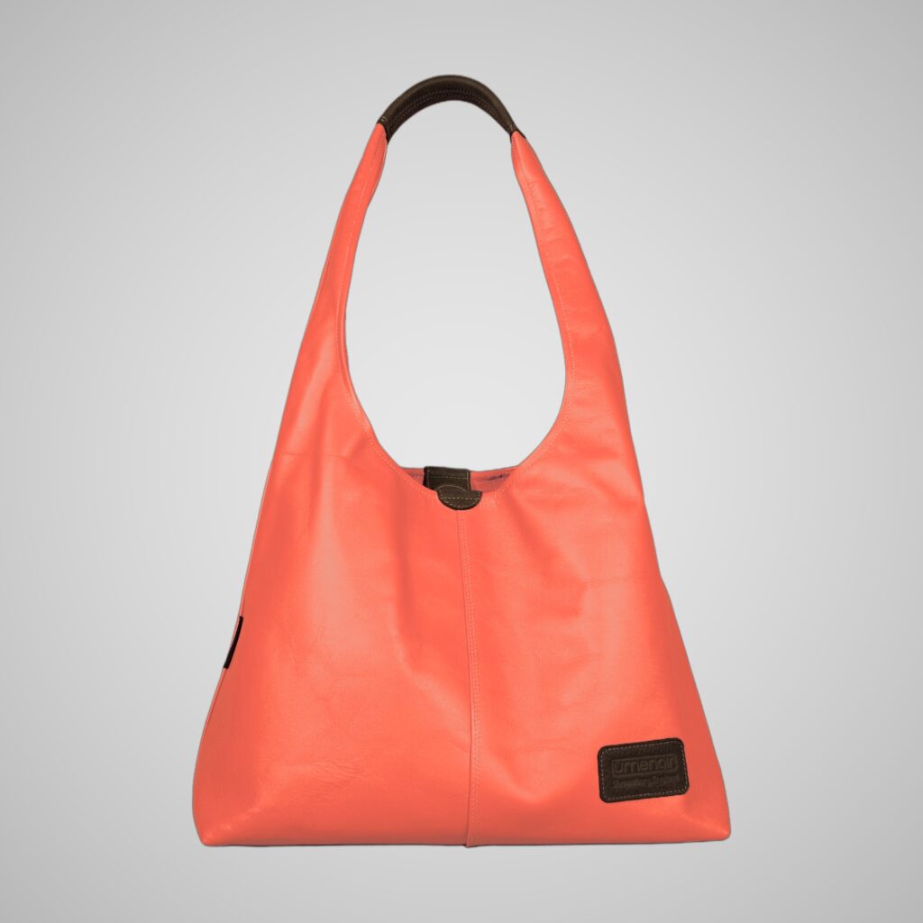 Front view of Lumengin XL hobo bag in bright orange smooth Italian leather with dark grey handle wrap, dark grey tab and Lumengin label, on soft grey