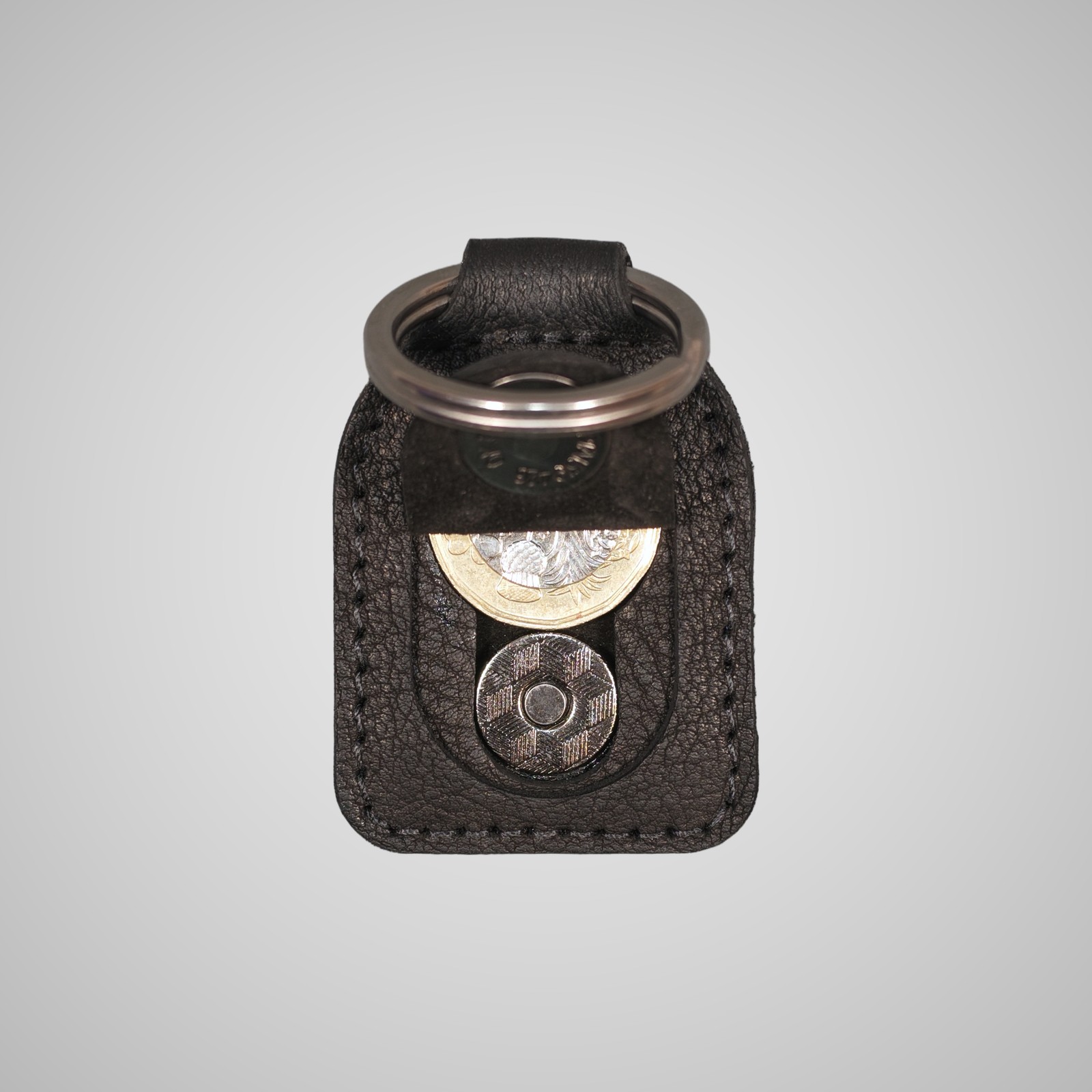 Lumengin black Janus calf £1 coin holder keyring, opened, holding a £1 coin, on soft grey background