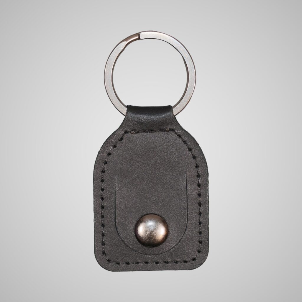 Lumengin black vegetable tanned leather £1 coin holder keyring, front view on soft grey background