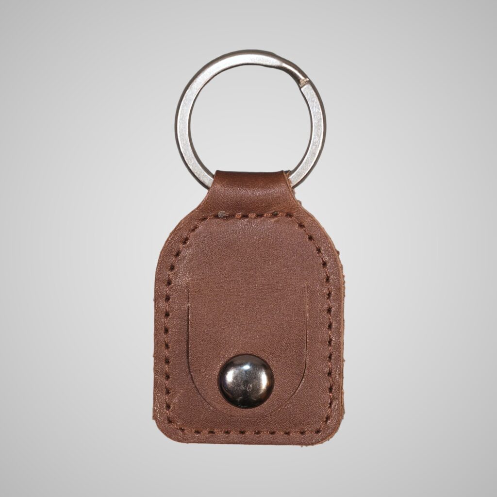 Lumengin mid brown vegetable tanned leather £1 coin holder keyring, front view on soft grey background