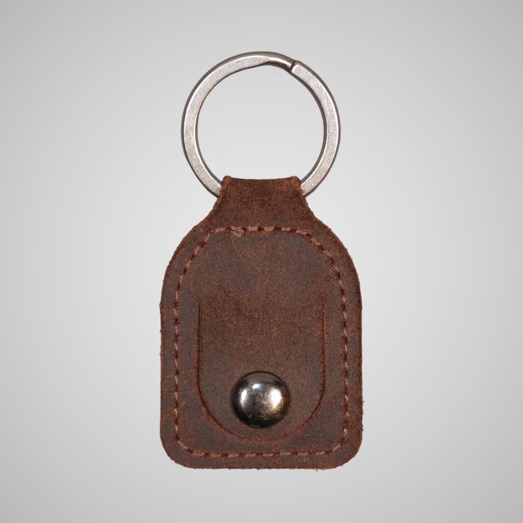 Lumengin waxy brown vegetable tanned leather £1 coin holder keyring, front view on soft grey background