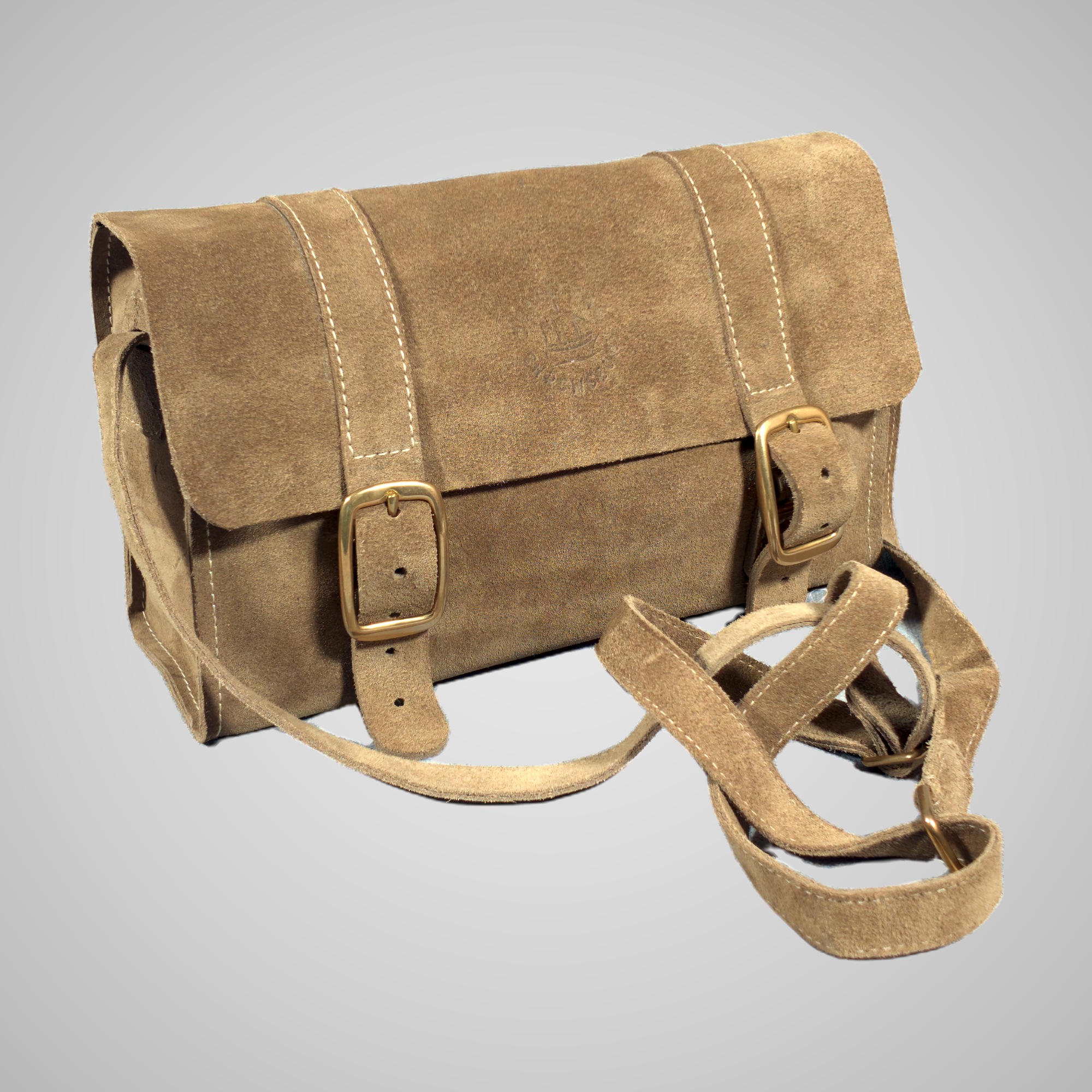 Three-quarter front view of the Lumengin Sand calf suede cross-body bag, showing the brass buckles and adjustable strap, on soft grey