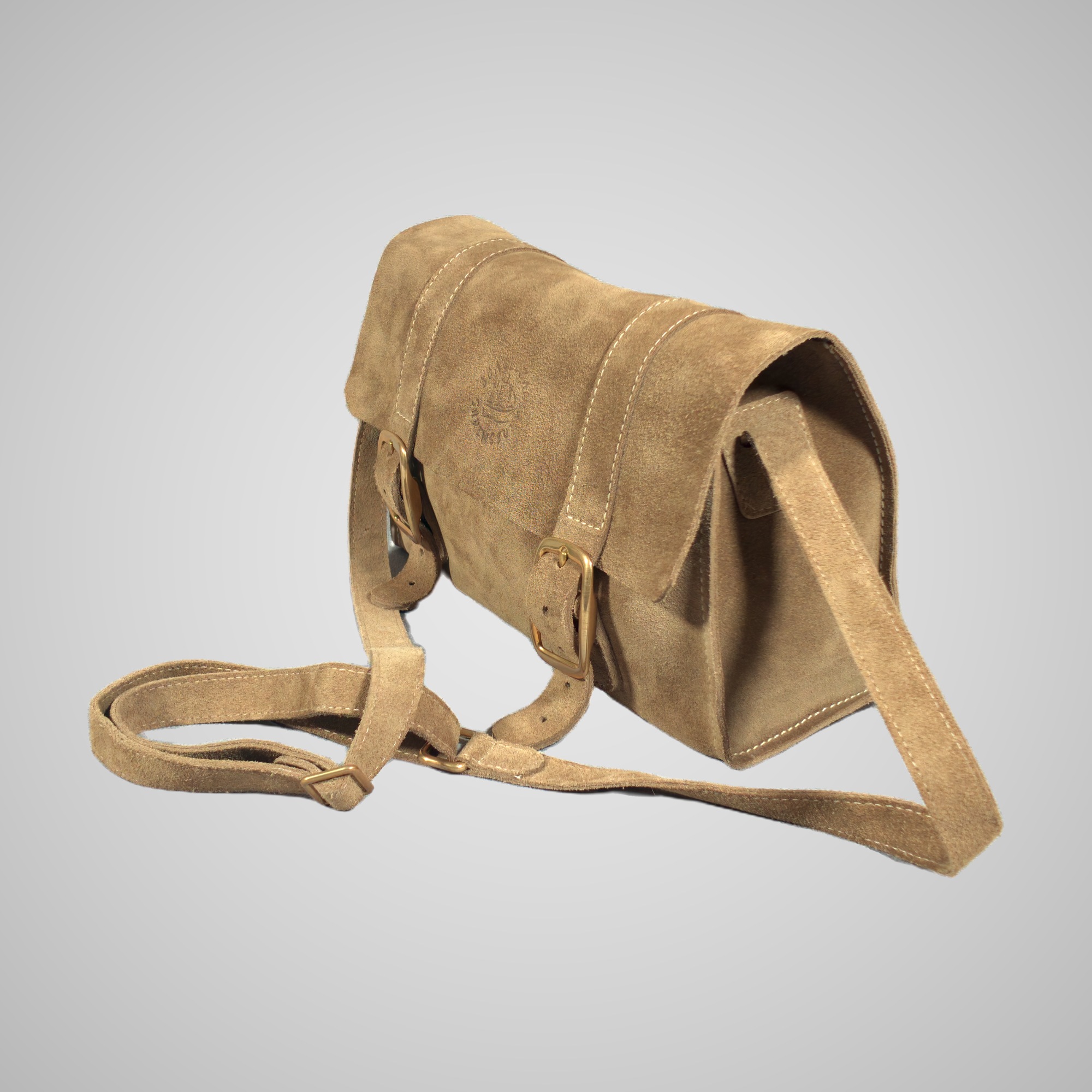 Three-quarter view of the Lumengin Sand calf suede cross-body bag, with its matching suede strap draped, on soft grey
